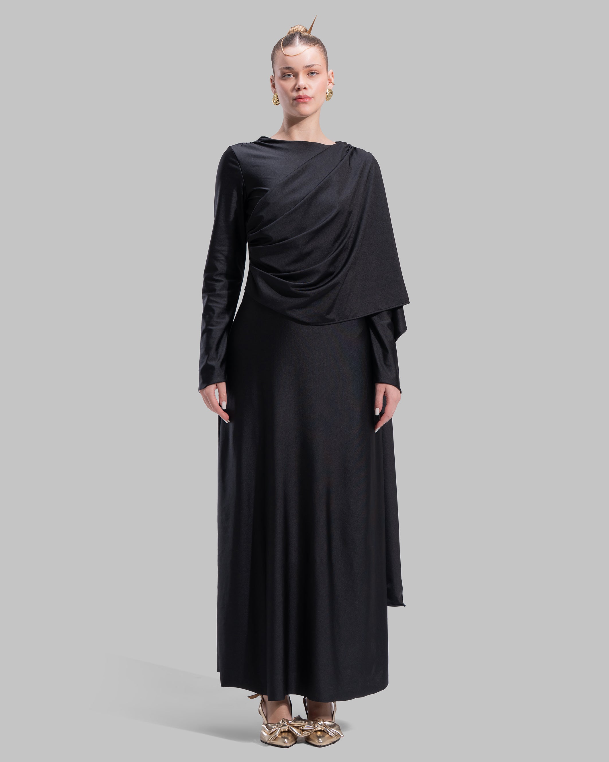 Long draped dress with a round neckline and asymmetrical overlay detail.