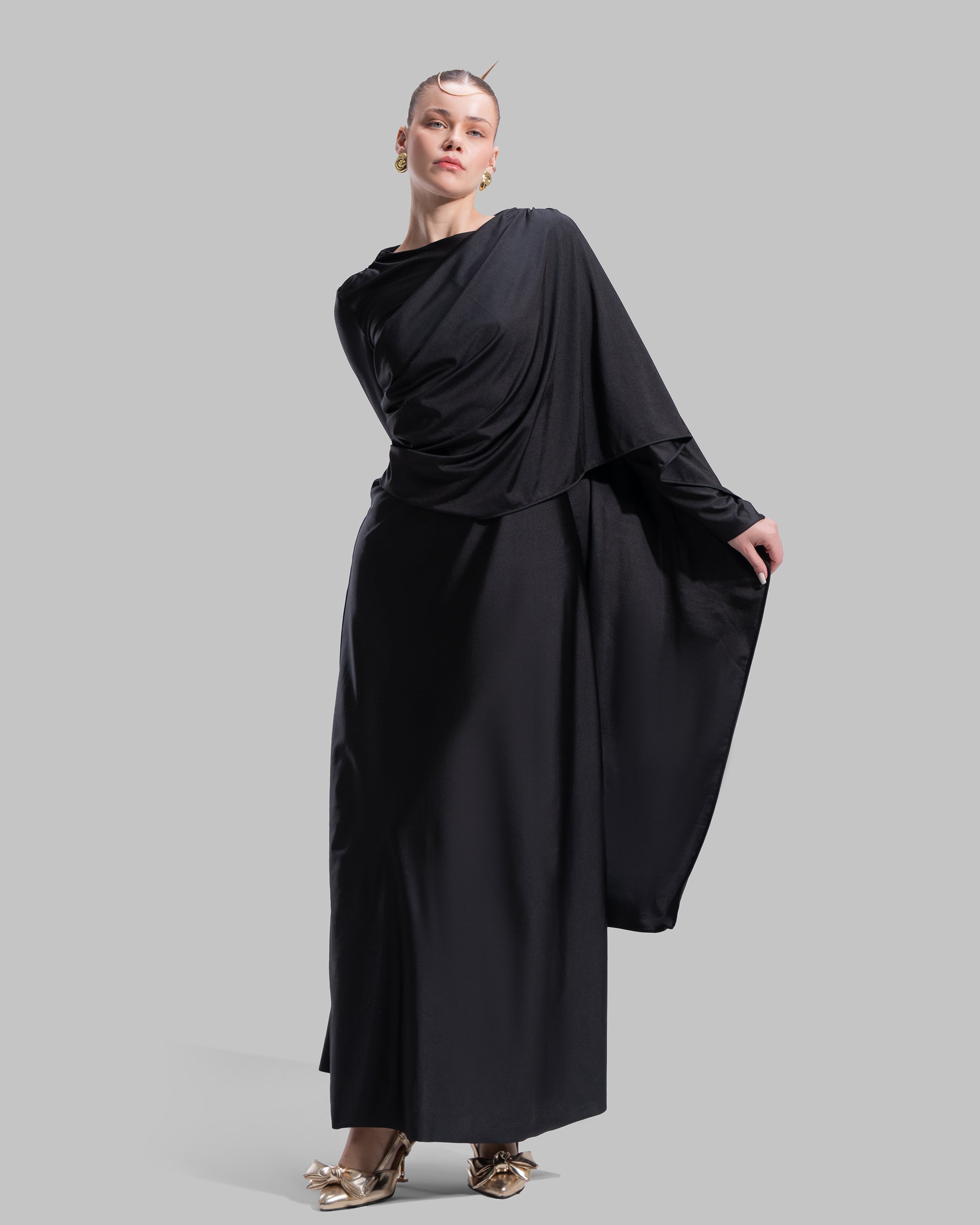 Long draped dress with a round neckline and asymmetrical overlay detail.