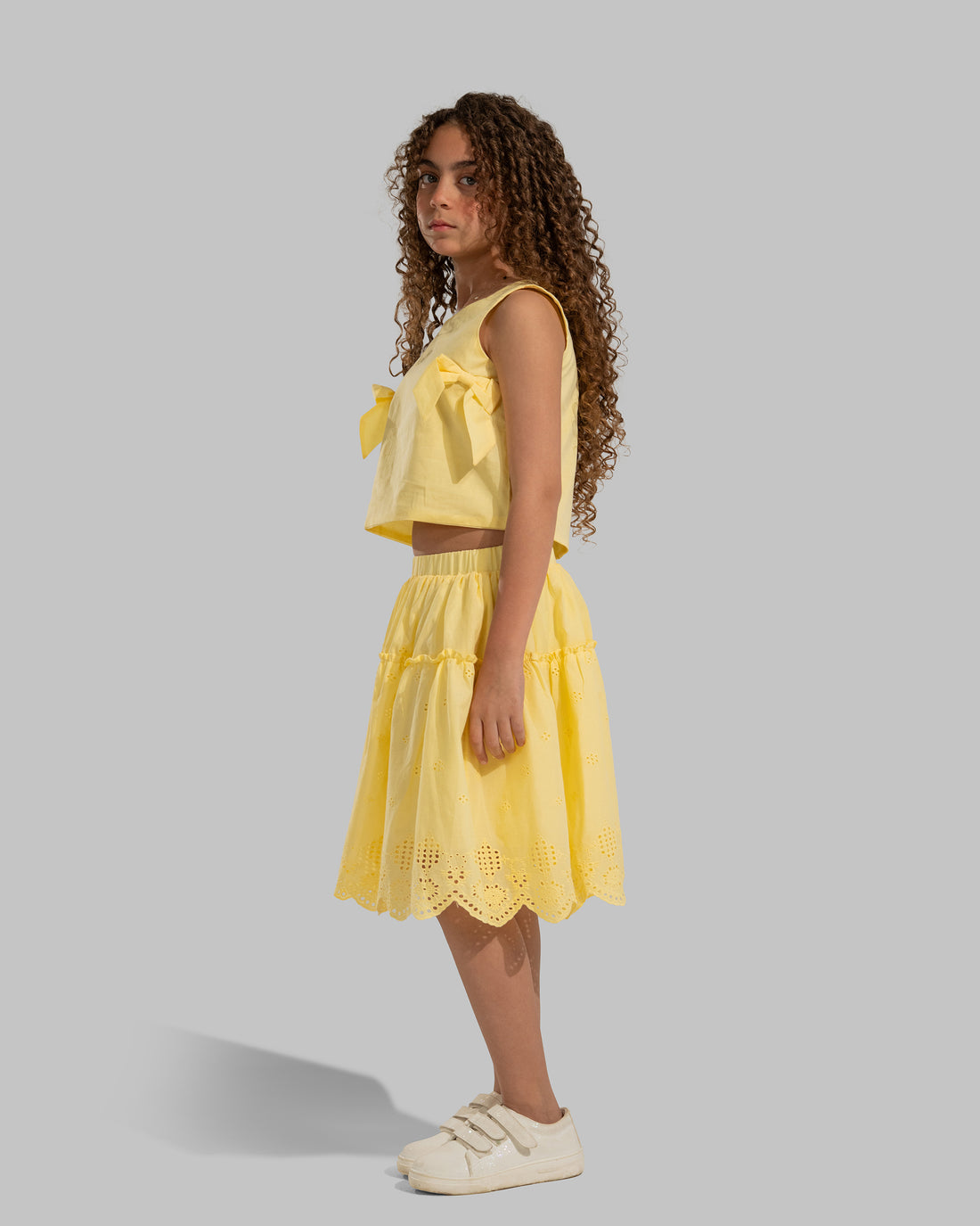 Sleeveless round neck top featuring decorative bows on the sides.