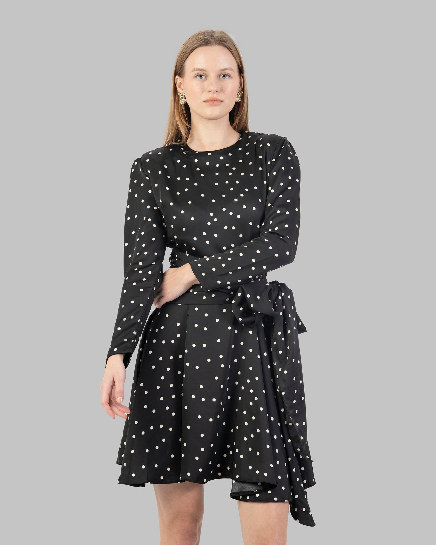 A chic polka dot mini dress with long sleeves and a stylish wrap-around tie waist