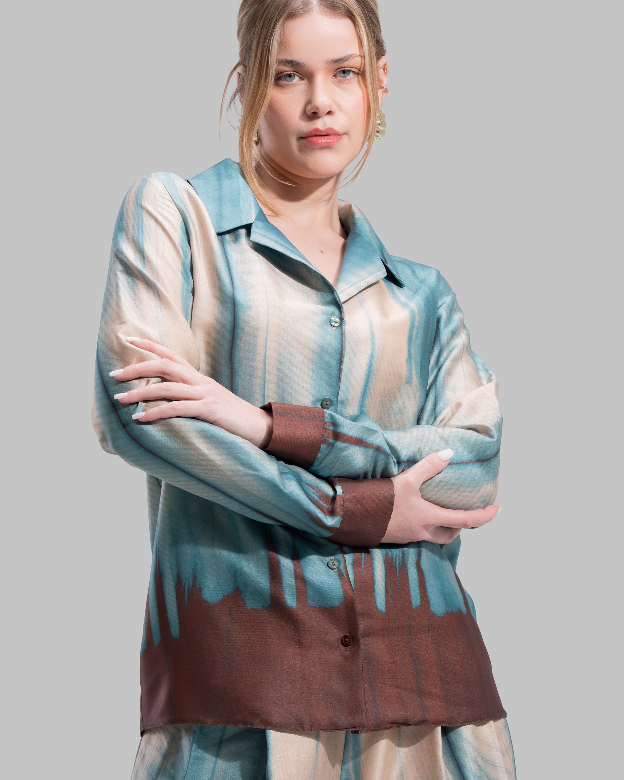 A long-sleeved button-down shirt featuring a teal and cream gradient print with a dark brown hem.