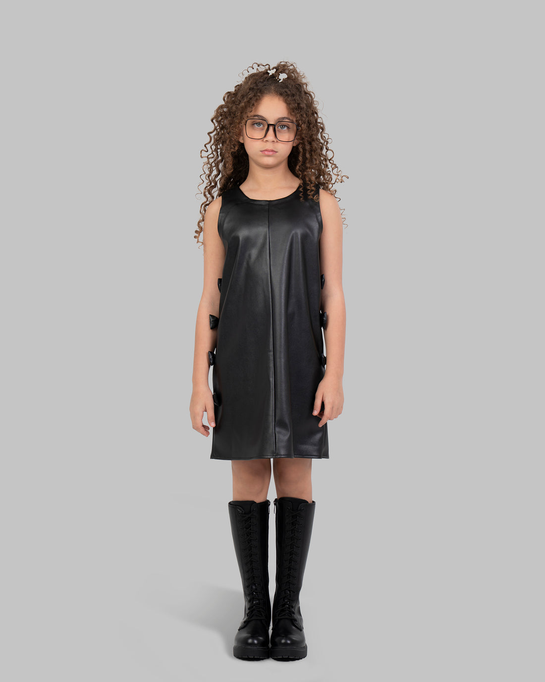 فستان مريلة من الجلد مزين بفيونكة جانبية.