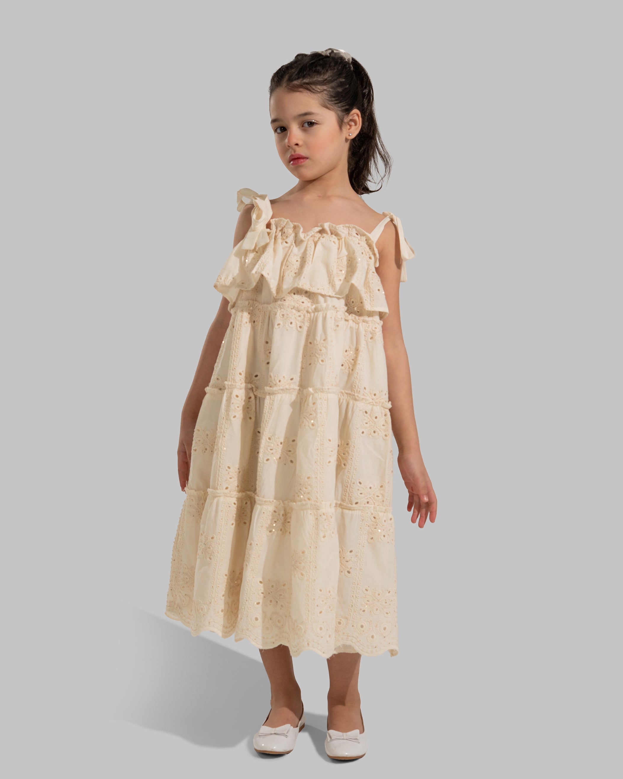 Tiered dress with perforated embroidery, ruffle trim, and tie-up shoulder straps.