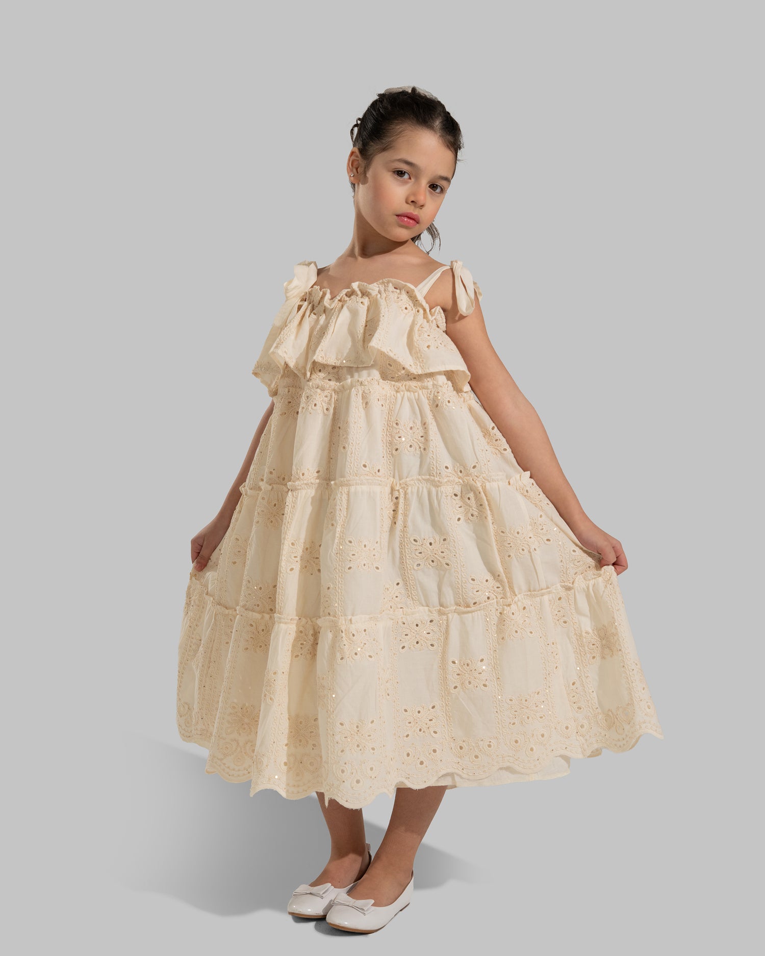 Tiered dress with perforated embroidery, ruffle trim, and tie-up shoulder straps.