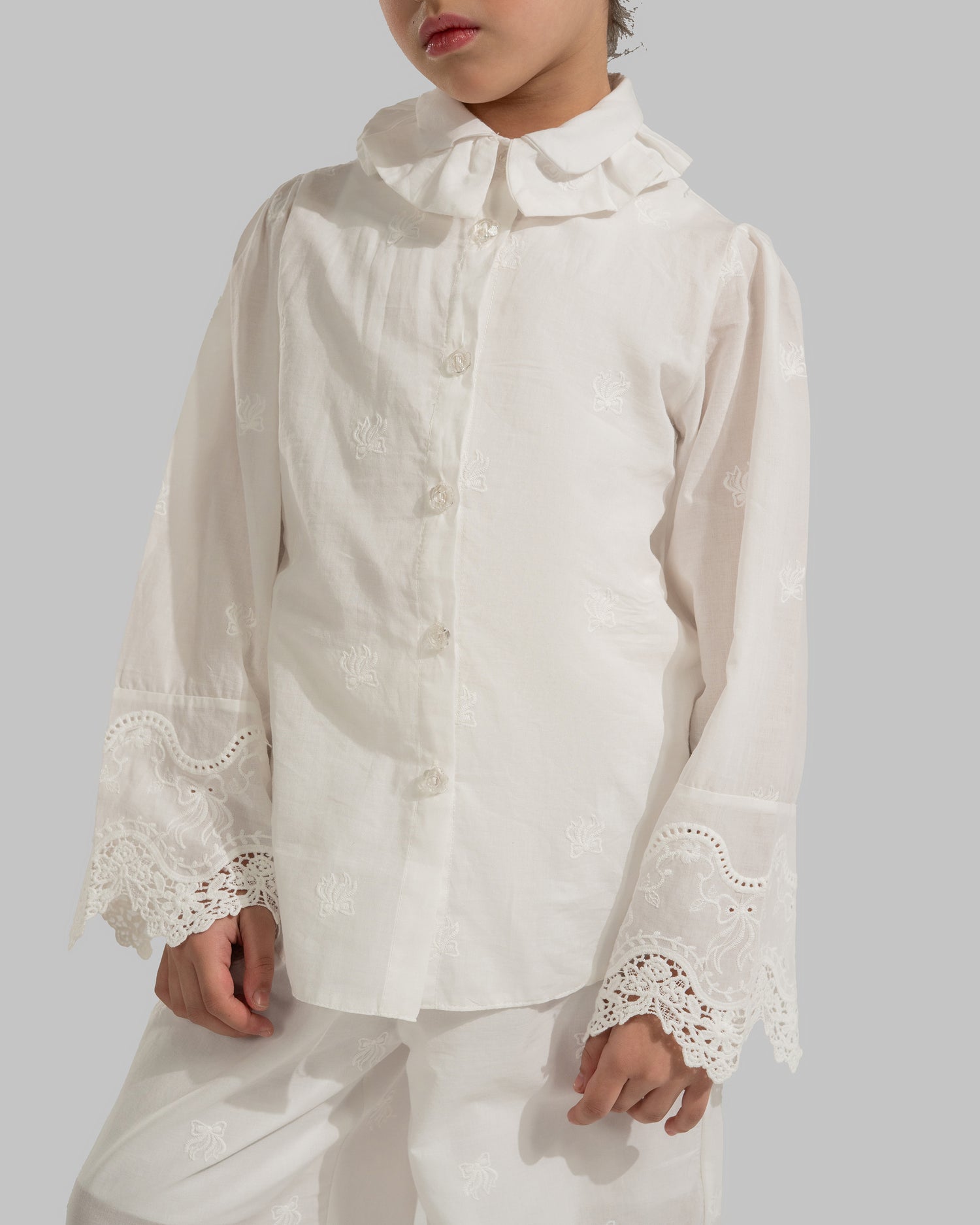 Button-up blouse with a ruffled collar and embroidered lace cuffs.